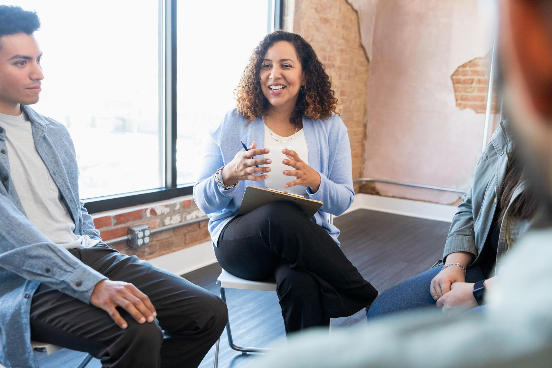 Therapy group meets with mid adult female counselor